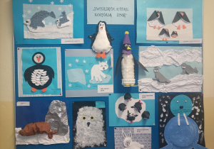 Na tablicy umieszczone są prace plastyczne, wykonane przez dzieci na konkurs plastyczny pt. "Zwierzęta, które kochają zimę". Na niebieskim tle znajdują się: pingwin, mors, foka, niedźwiedź polarny, sowa, zając polarny.