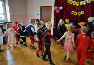 dzieci w strojach karnawałowych tworzą węża w tańcu.