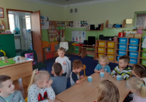 Dzieci siedzą przy stole. Czworo z nich ma jescze kubki z koktajlem.