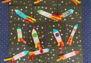 Prace plastyczne- na czarnych kartonach naklejone są kolorowe rakiety kosmiczne.