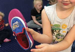 Dziewczynka trzyma but, którym odmierzała długość.