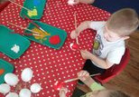 Dzieci siedzą przy stole i malują jajka.