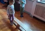 Dziewczynka mierzy długość ławki stopami.