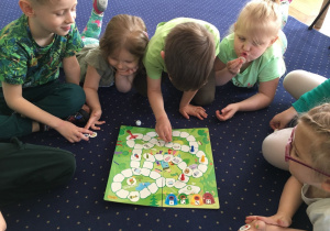 Dzieci na podłodze grają w ekologiczną grę planszową.