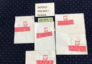 Na podłodze leża flagi Polski z orłem wykonane przez dzieci - układanka dla dzieci starszych..