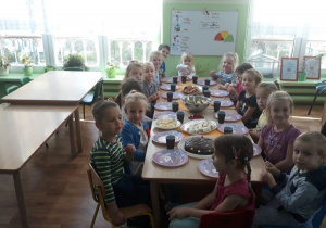 Wszystkie dzieci siedzą przy stole.