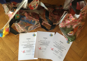Na podłodze ułożone są dyplomy i nagrody dla dzieci, które brały udział w konkursie.