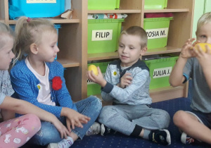 Dzieci oglądają i przekazują sobie owoce.
