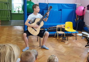 Uczeń szkoły muzycznej gra koncert na gitarze dla dzieci.