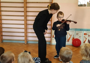 Chłopiec próbuje grać na skrzypcach.