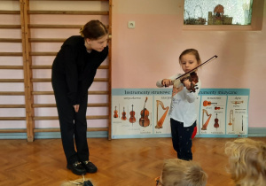 Dziewczynka prezentuje swoje umiejętności gry na skrzypcach.