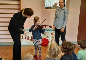 Dziewczynka próbuje grać na skrzypcach.