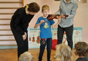 Chłopiec próbuje grać na skrzypcach.