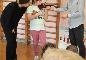 Dziewczynka próbuje grać na skrzypcach.