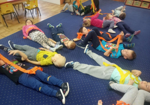 Dzieci leżą na dywanie po zakończeniu swojego tańca.