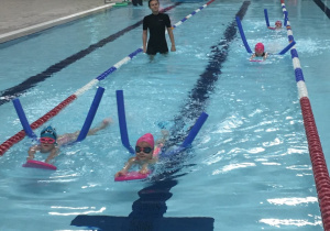 Dzieci pływają z wykorzystaniem desek.