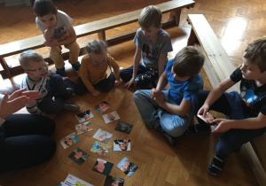 Dzieci siedzą na podłodze i ogladają zdjęcia prezentujące różne emocje.