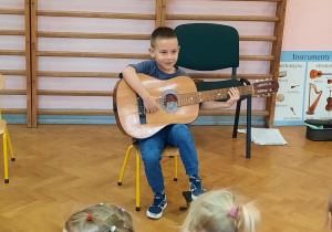 Chłopiec prezentuje swoje umiejętności gry na gitarze.