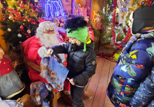 Chłopiec odbiera prezent od Świętego Mikołaja.