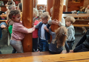 Dzieci bawią się przytulając do drewnianych pali.