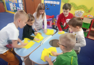 dzieci sprzątają salę przy pomocy żółtych ściereczek