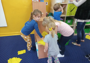 dzieci sprzątają salę przy pomocy żółtych ściereczek