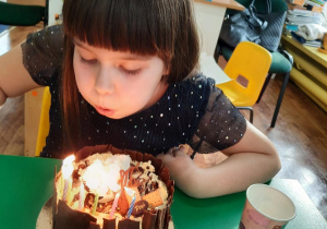 Dzieczynka zdmuchuje świeczki na torcie.