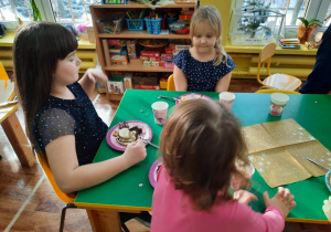 Dzieci siedzą przy stole i zjadają tort.