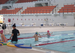 Dzieci wykonują ćwiczenia w basenie.