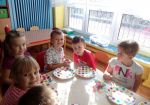 dzieci przy stolikach świętują urodziny.