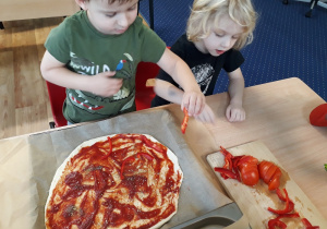 dzieci samodzielnie dekorują pizzę