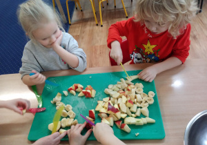 dzieci kroją owoce na plastikowych tacach