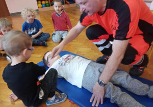 praktyczne zajęcia z udzielania pierwszej pomocy, na materacu leży chłopiec, pomocy udziela ratownik medyczny