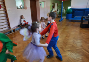 Dziewczynka i chłopiec tańczą w kółeczku.