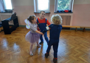 Troje dzieci tańczy w kółeczku.