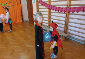 dziewczynka i chłopiec tańczą z balonem