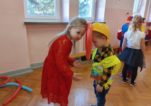 dziewczynka i chłopiec tańczą z balonem