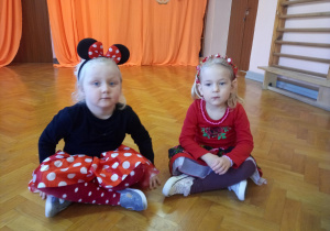 dwie dziewczynki siedzą na podłodze na sali gimnastycznej