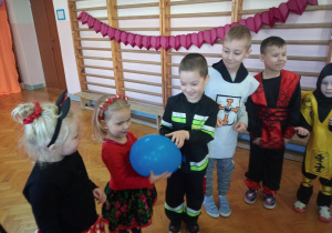 dzieci w kółeczku bawią się przy muzyce i podają sobie balon