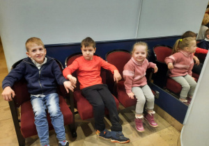 Troje dzieci siedzi na krzesłach podczas przerwy.