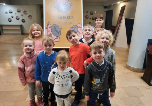 Dzieci z grupy IV pozują przy afiszu "Świnki 3".