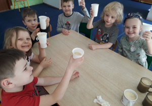 Dzieci siedzą przy stole i piją wykonany przez siebie koktajl.