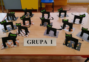 na stoliku widać przestrzenne koty wykonane z czarnego papieru