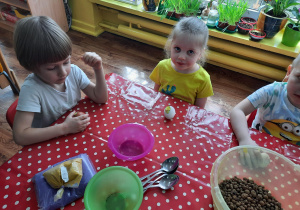 dzieci przy stoliku, na nim miseczki z kolorowym piaskiem