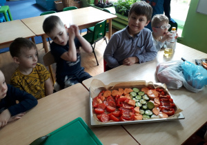 dzieci siedzą przy stoliku, na którym widać pokrojone warzywa
