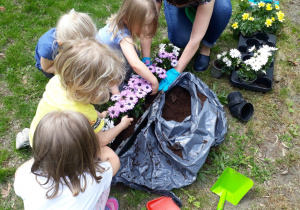 Dziewczynki sadzą kwiaty do skrzynki.