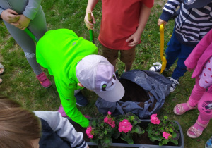 Dzieci sadzą kwiaty w skrzyniach.
