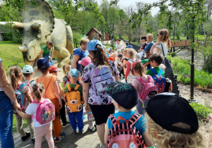 Dzieci oglądają i poznają dinozaura.