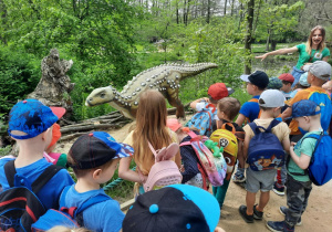 Dzieci oglądają i poznają dinozaura.