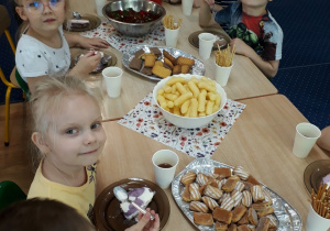 Dzieci siedzą przy stole i zjadają lody z galaretką.